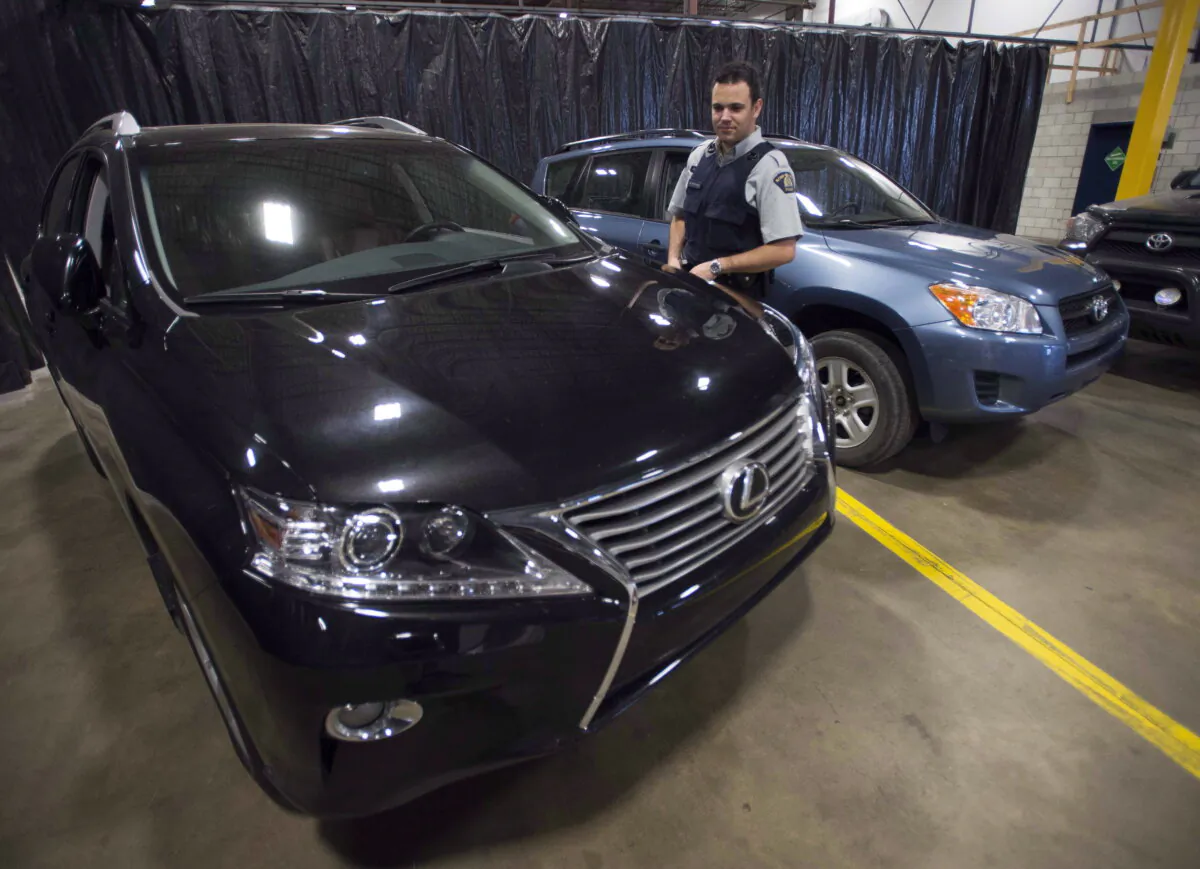 An RCMP officer looks at a stolen Lexus that was seized from a container in Montreal in a file photo. (The Canadian Press/Ryan Remiorz)