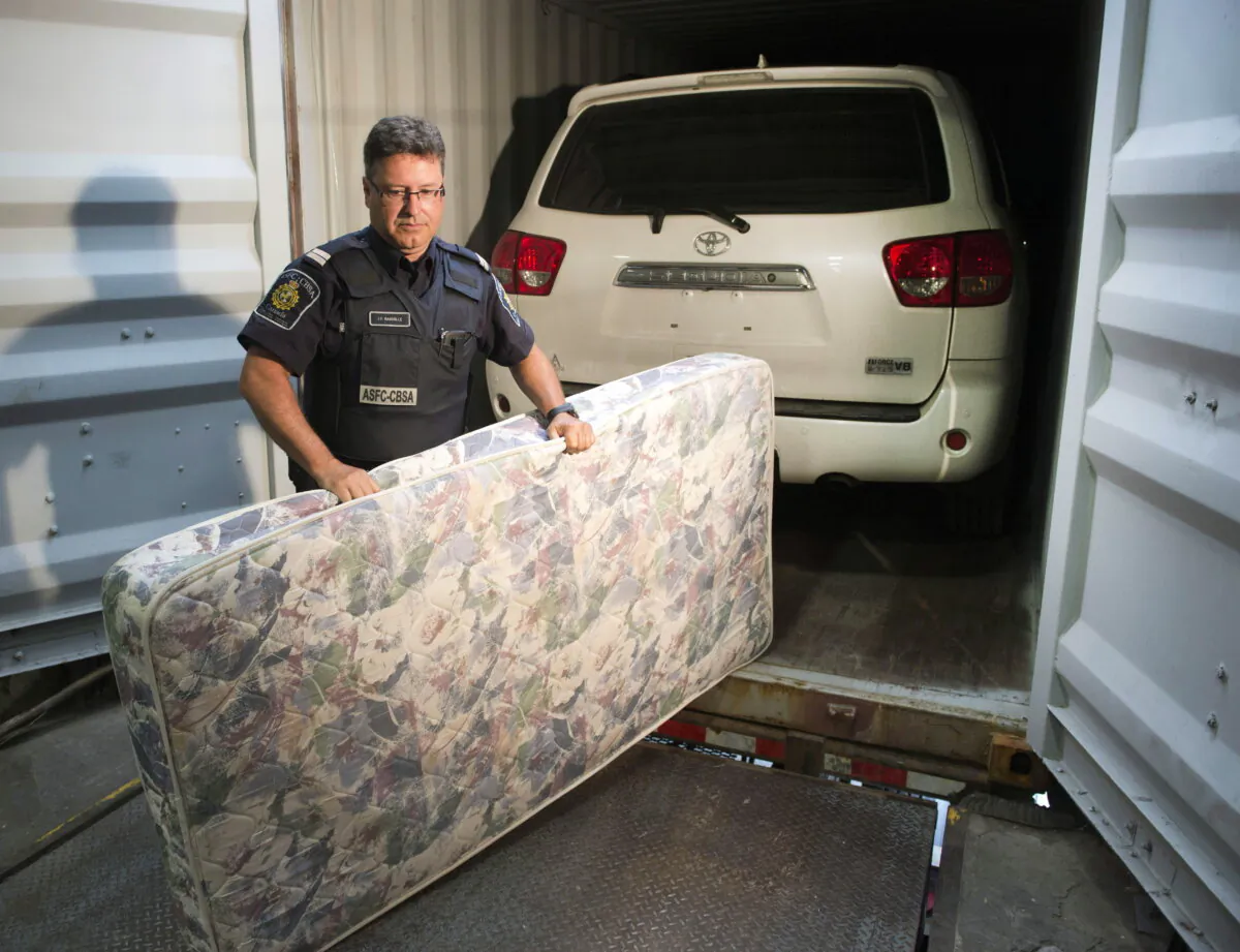 A file photo of a CBSA officer removing a mattress that was used to hide a stolen vehicle in a container in Montreal on July 17, 2014. (The Canadian Press/Ryan Remiorz)