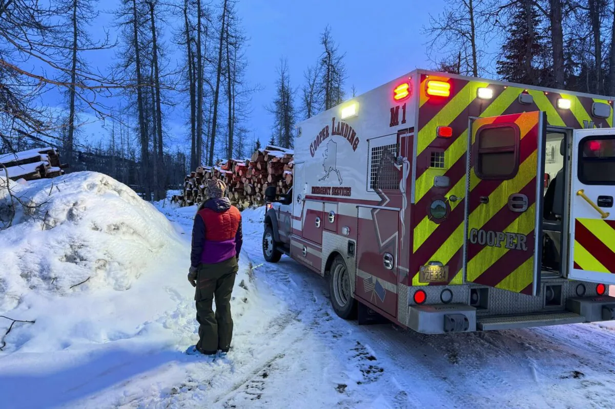 A member of the Cooper Landing EMS rescuers looks at the mountain to see if troopers are bringing down avalanche survivors in Cooper Landing, Alaska, on Feb. 13, 2024. (Clay Adam/Cooper Landing Emergency Services via AP)