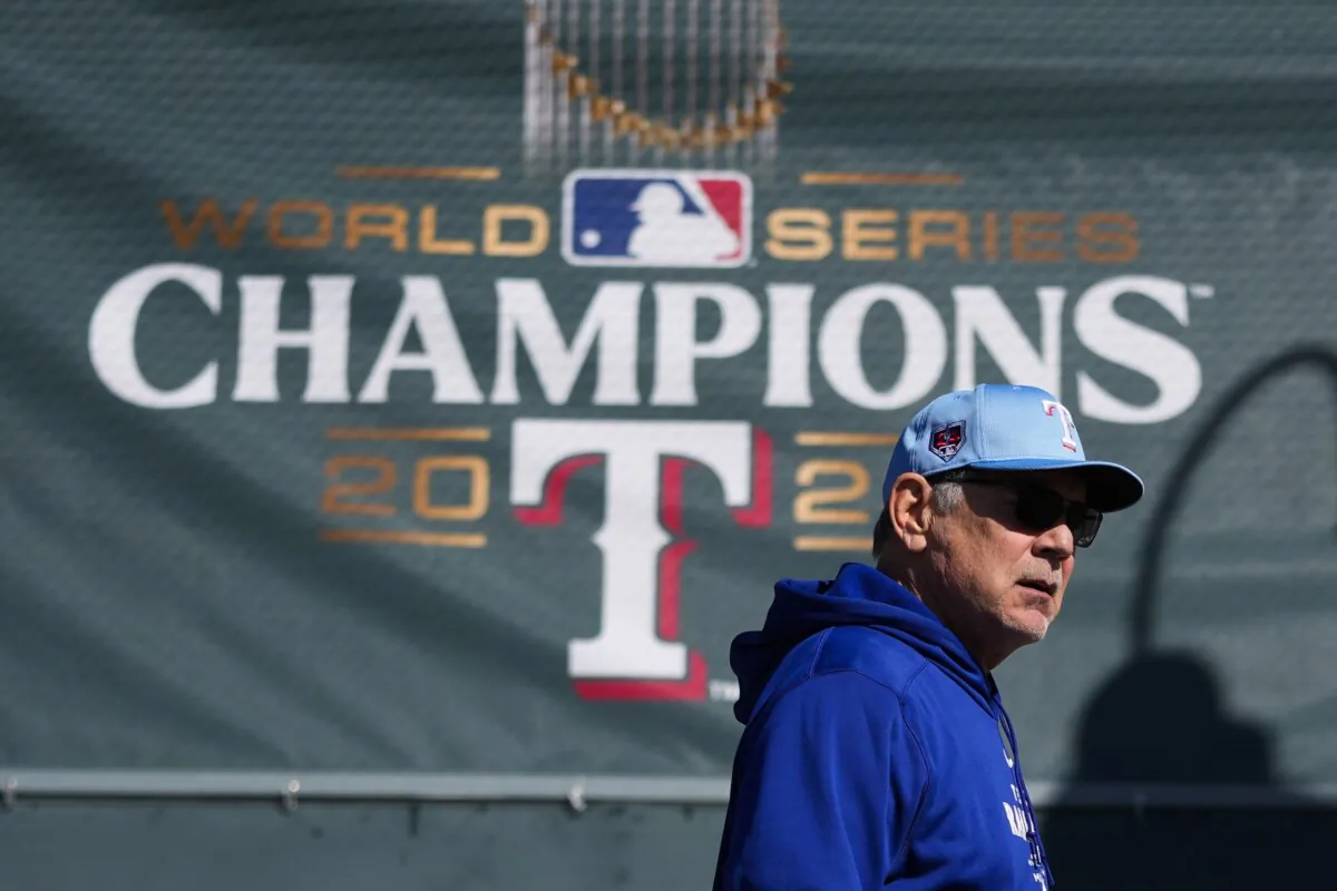 Texas Rangers manager Bruce Bochy walks by a 2023 World Series champions banner before his team's spring training baseball workouts in Surprise, Ariz., on Feb. 14, 2024. (Lindsey Wasson/AP Photo)