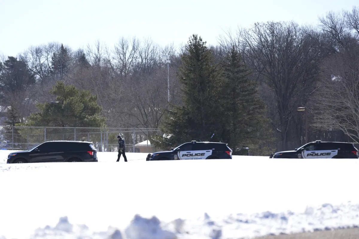 Law enforcement stand on a road after two police officers and a first responder were shot and killed in Burnsville, Minn., on Feb. 18, 2024. (Abbie Parr/AP Photo)