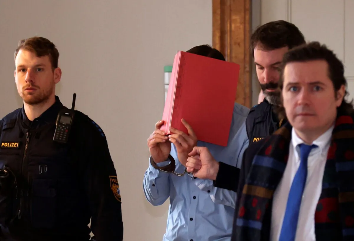 A 31-year-old American man accused of murder is led into the courtroom at the regional court in Kempten, Southern Germany, on Feb. 19, 2024. (Karl-Josef Hildenbrand/dpa via AP)