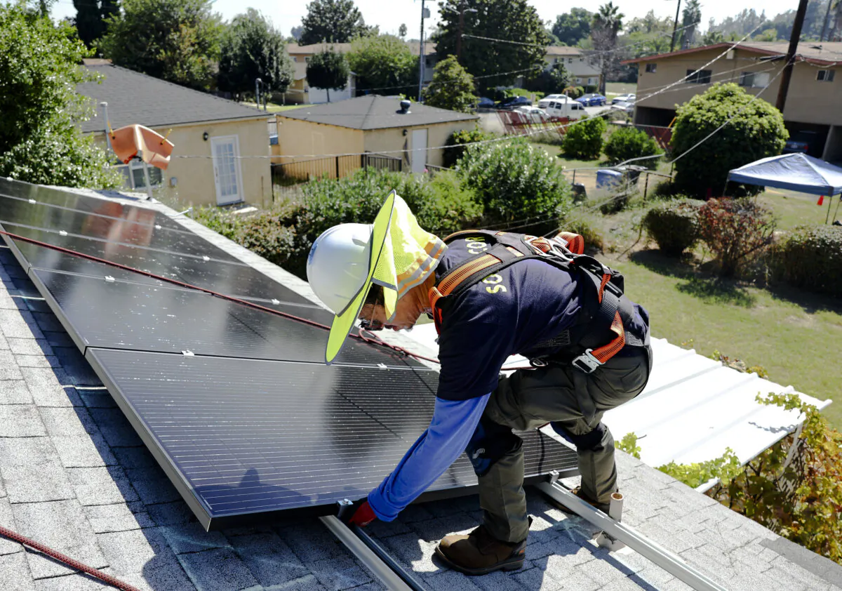 A worker installs solar panels on the rooftop of a house in Pomona, Calif., on Oct. 19, 2023. (Mario Tama/Getty Images)