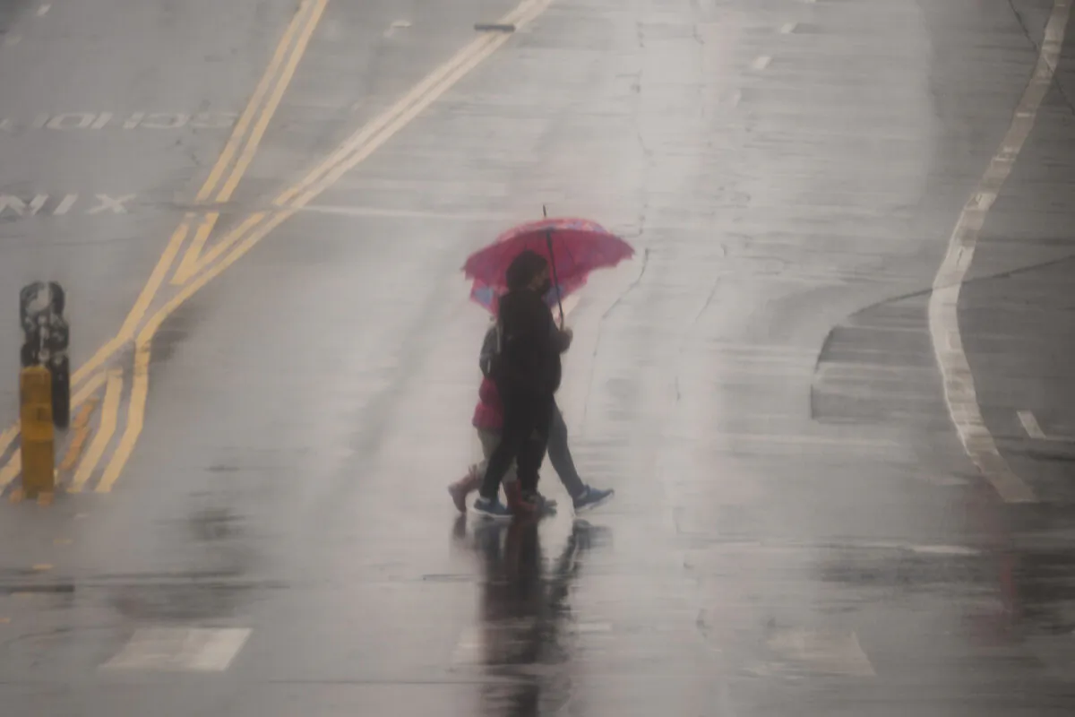 People cross the street with umbrellas in heavy rain in Los Angeles on Feb. 19, 2024. (Damian Dovarganes/AP Photo)