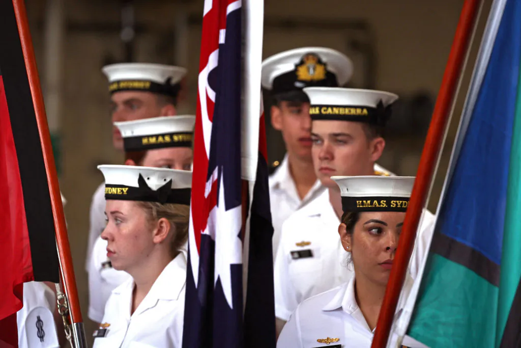 Sailors from the Royal Australian Navy stand behind flags aboard the Australian Navy ship HMAS Canberra in Sydney, Australia on Feb. 20, 2024. (David Gray/AFP via Getty Images)