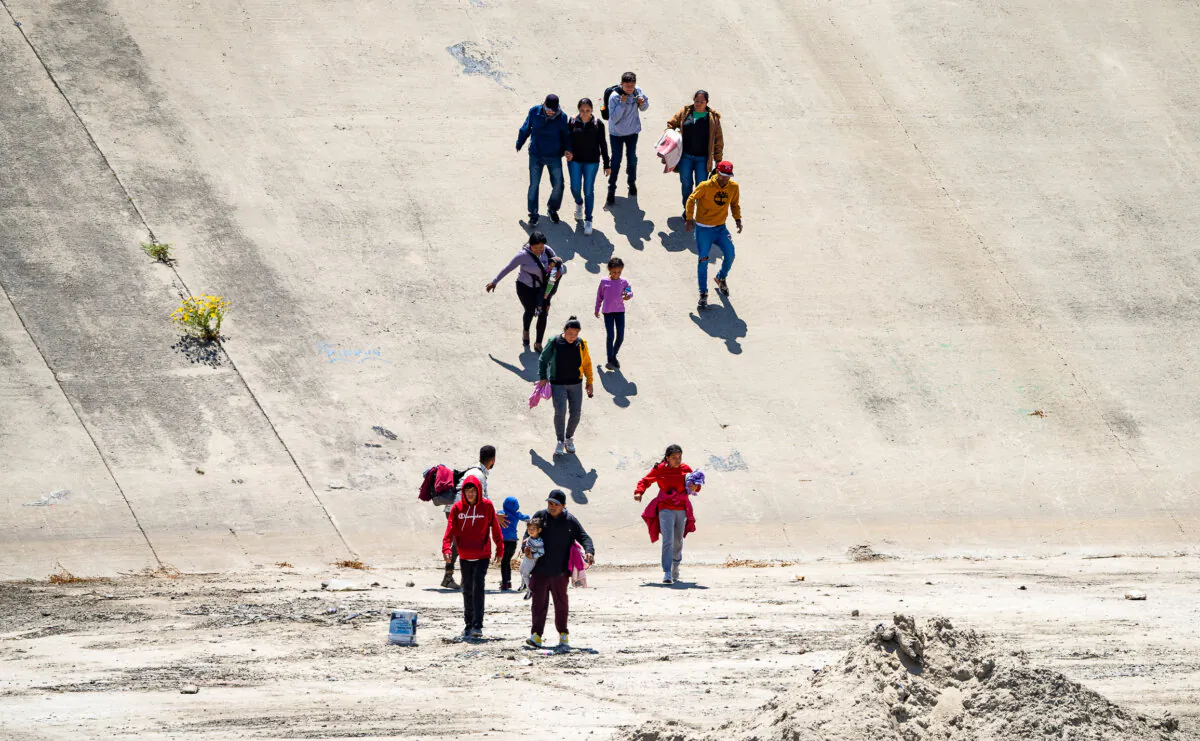 Migrants cross the Tijuana River bed towards the San Diego port of entry to the United States on May 11, 2023. (John Fredricks/The Epoch Times)