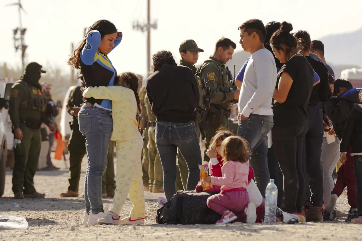 Illegal aliens wait outside a processing station near the Lukeville Port of Entry in southern Arizona on Dec. 7, 2023. (Allan Stein/The Epoch Times)