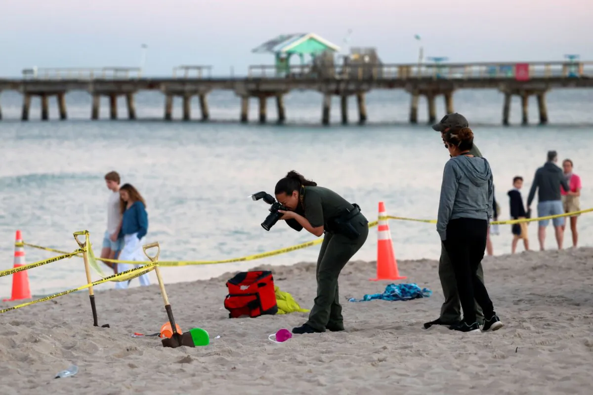 Investigators on the beach in Lauderdale-by-the-Sea, Fla., take photos of the scene of a sand collapse on Feb. 20, 2024. (Mike Stocker/South Florida Sun-Sentinel via AP)