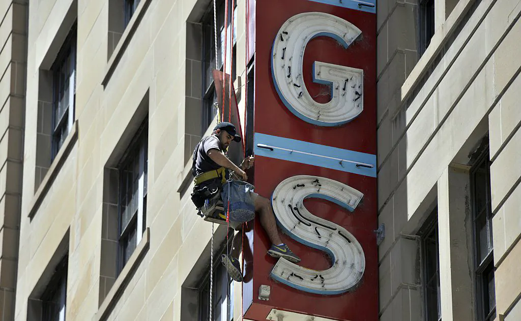 A man fixes a neon sign board displayed outside a building in Sydney on Feb. 3, 2015.  (Saeed Khan/AFP via Getty Images)