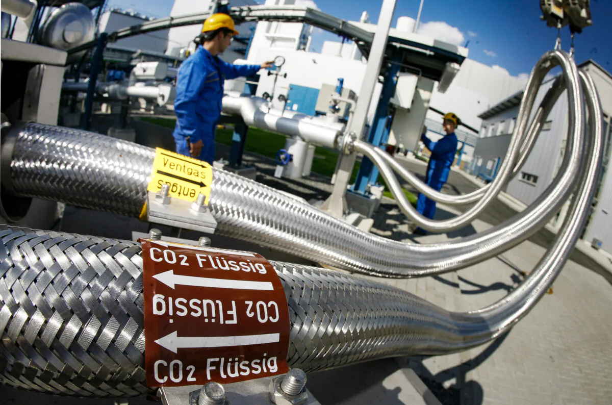 Two employees work on pipes carrying liquid CO2 at the Schwarze Pumpe power station in Brandenburg, Germany, on Sept. 8, 2008. (Michael Urban/ DDP/AFP via Getty Images)