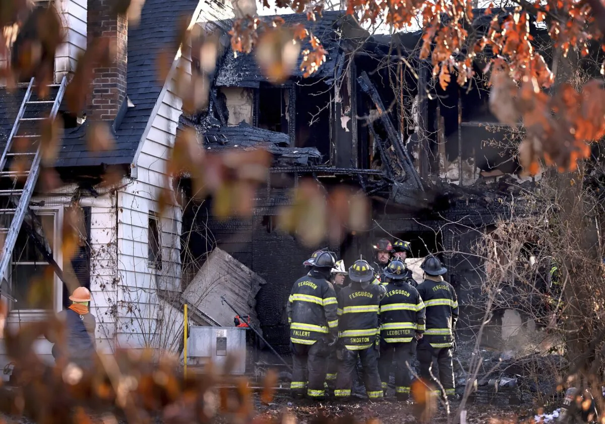 Firefighters gather around a burned out section of a home after they extinguished the flames of house fire in Ferguson, Mo., on Feb. 19, 2024. (David Carson/St. Louis Post-Dispatch via AP)