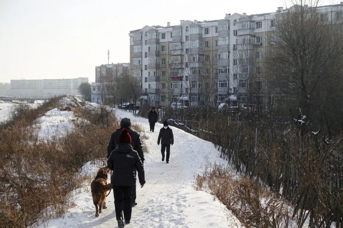People walk next to residential buildings in the coal city of Hegang, Heilongjiang Province, China on Jan. 2, 2020. (Ryan Woo/Reuters)