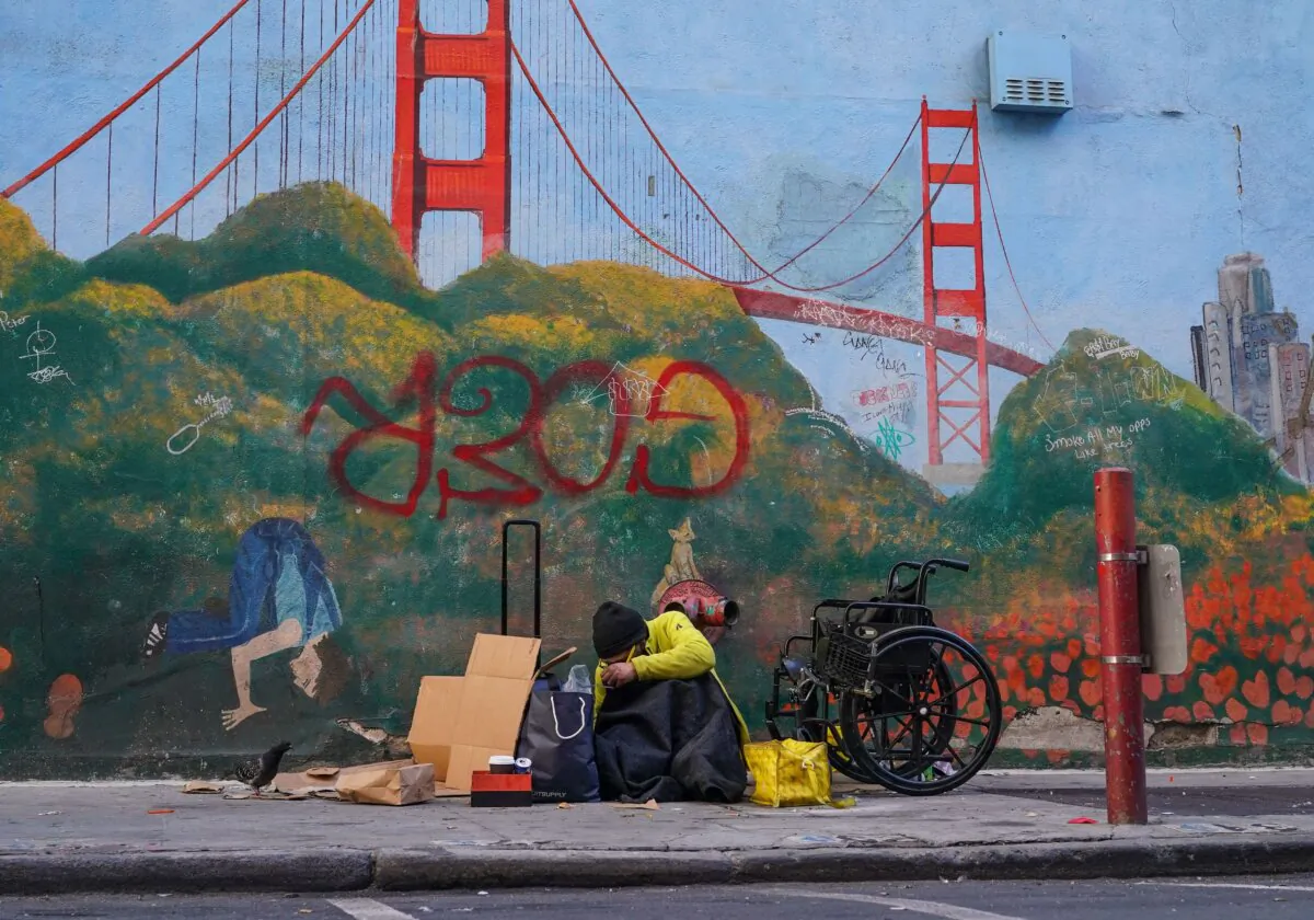 A homeless person lies against a mural of the Golden Gate Bridge in downtown San Francisco on Nov. 11, 2023. (Loren Elliott/AFP via Getty Images)