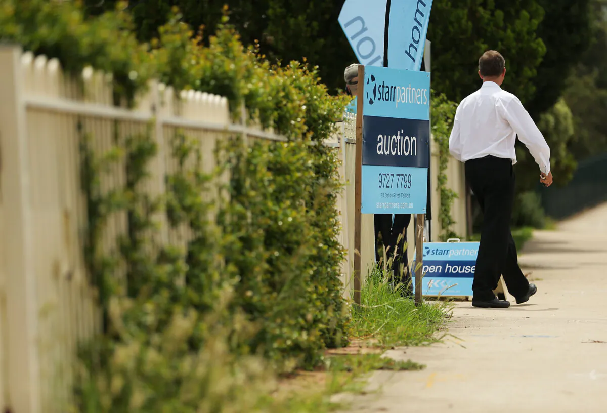 A real estate agent stands near an auction sign in Blacktown, Australia, on Feb. 14, 2015. (Mark Metcalfe/Getty Images)