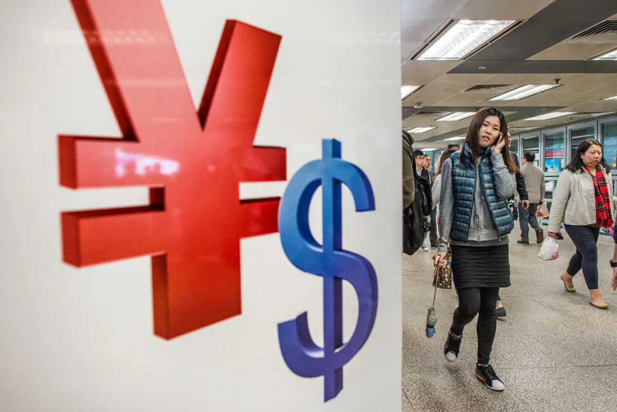 A woman walks past Chinese yuan and U.S. dollar symbols in Hong Kong, on Nov. 28, 2012. (Philippe Lopez/AFP via Getty Images)