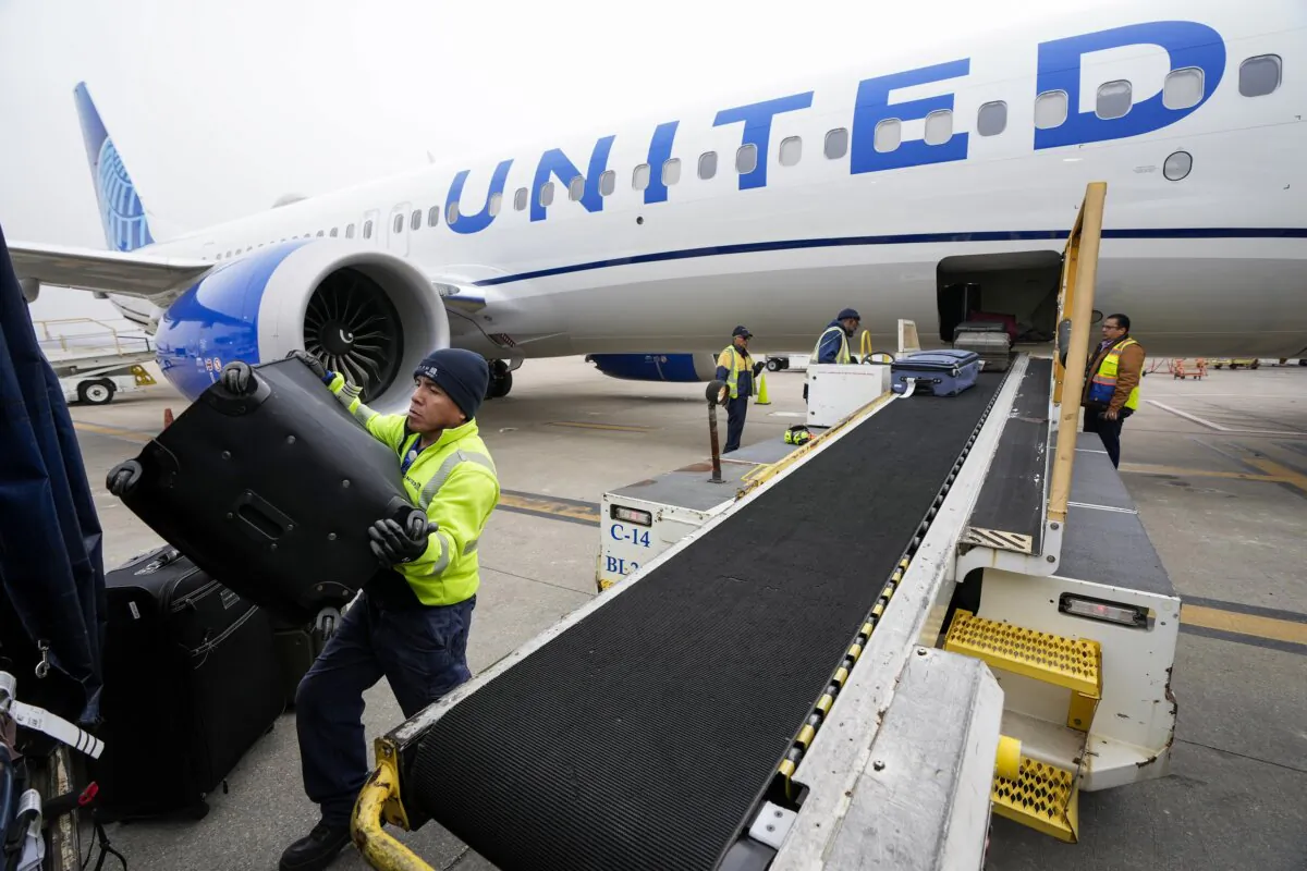 Juan Chavez handles baggage as is comes off a United Airlines aircraft upon landing at George Bush Intercontinental Airport in Houston on Dec. 21, 2023. (Brett Coomer/Houston Chronicle via AP)
