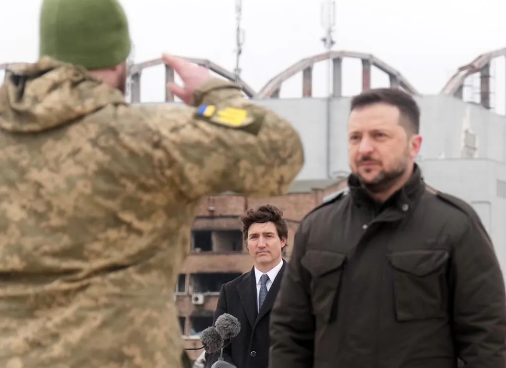 Canadian Prime Minister Justin Trudeau watches as Ukrainian President Volodymyr Zelenskyy takes a salute during a ceremony at Hostomel Airport in Kyiv on Feb. 24, 2024. (The Canadian Press/Nathan Denette)