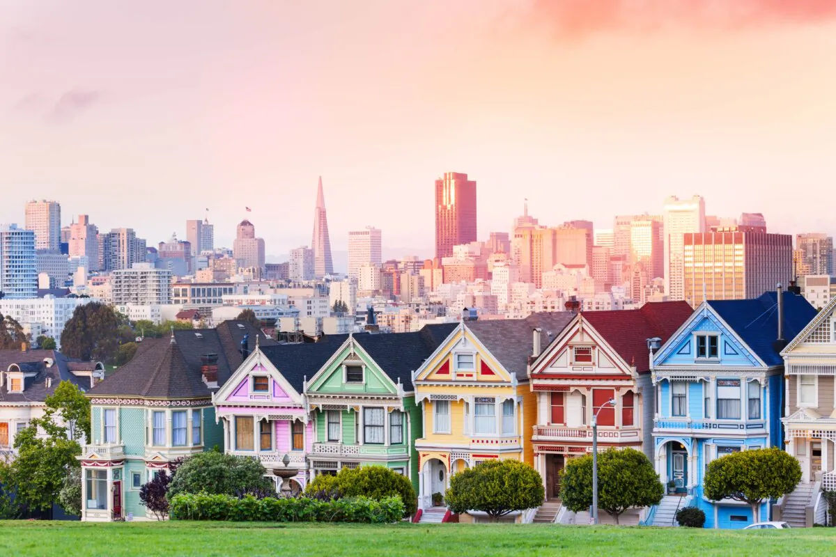 The painted ladies of Steiner Street, as seen from Alamo Square Park, with downtown San Francisco in the background. The colors of the houses are clean and crisp, and the white trim makes the porches and arcade columns stand out. Some of the porches are arched. All have ornate gingerbread trim, with some featuring brighter accent colors. (Sergey Novikov/Shutterstock)