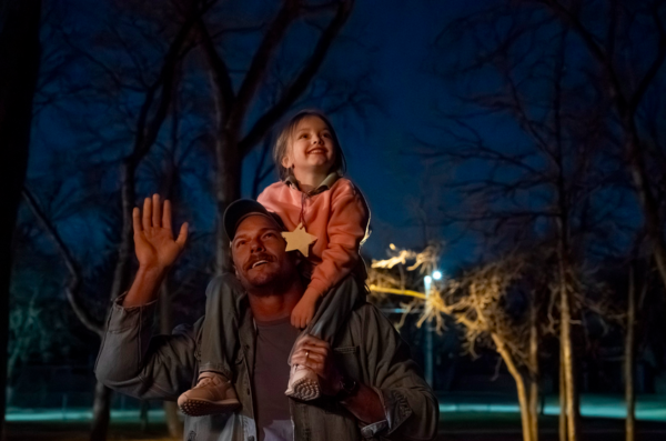 Man with little girl on his shoulders in ORDINARY ANGELS