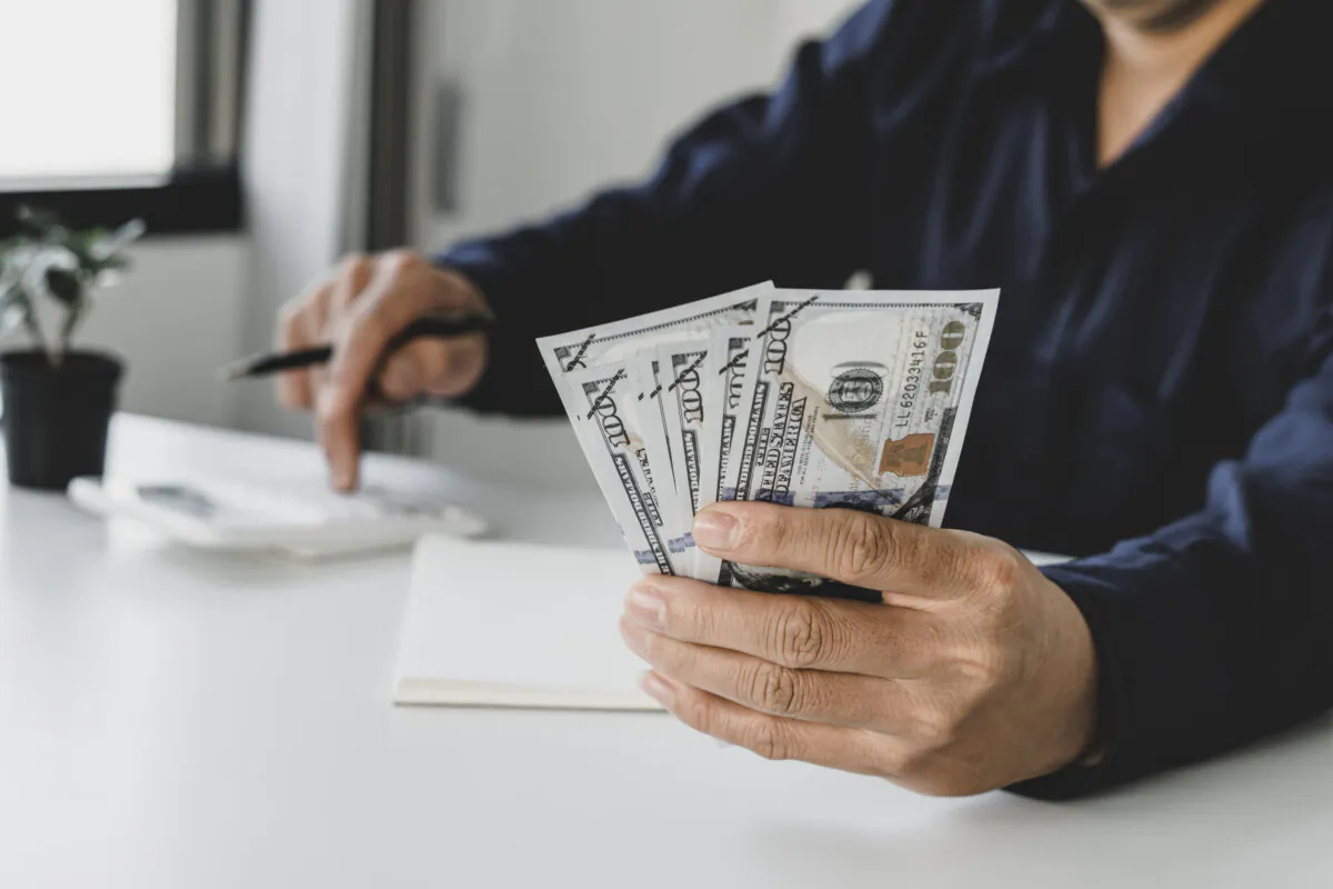 Financial, economy and home savings ideas Businessman grasping money and calculating financial budgets for future emergency use.
