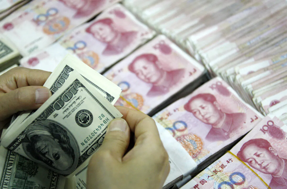 This picture taken on September 24, 2013 shows US dollar notes being counted next to stacks of 100 yuan (RMB) bank notes at a bank in Huaibei, in eastern China's Anhui province. With deals from London to Singapore, China is seeking a greater role for its yuan currency in global markets to challenge the hegemony of the almighty dollar. (STR/AFP via Getty Images)