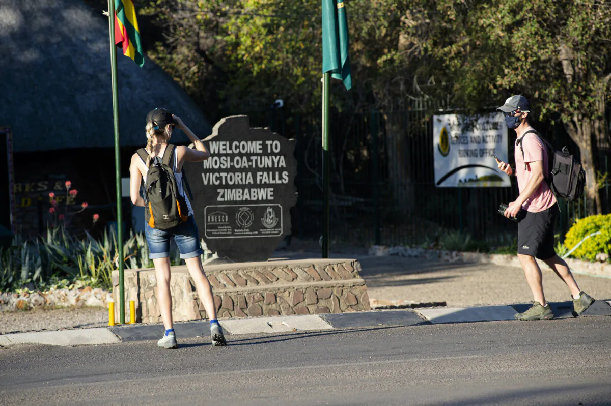 Tourists wear face masks at the entrance of the Victoria Falls in Victoria Falls, Australia, on Aug. 6, 2021. (Tichaona Muketiwa/AP Photo)