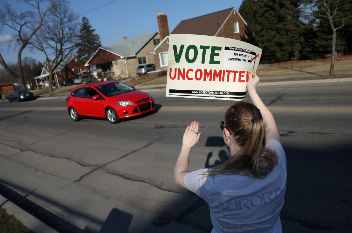 A Democratic voter uncommitted to President Joe Biden rallies outside of a polling location as a car drives past at Oakman Elementary School in Dearborn, Michigan, on Feb. 27, 2024. (Kevin Dietsch/Getty Images)