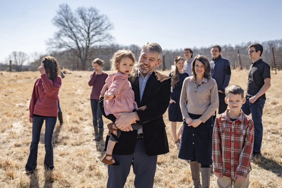 Paul Vaughn holds his youngest daughter alongside his wife Bethany Vaughn and 8 of their 11 children, in the backyard of their home in Centerville, Tenn., on Feb. 20, 2024. (Samira Bouaou/The Epoch Times)