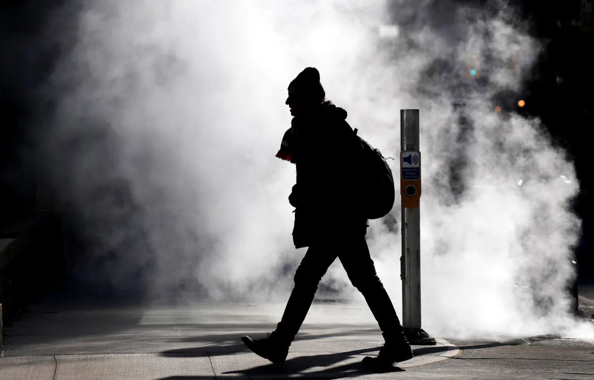 A man walks through steam in the cold winter weather in Toronto, on Feb. 3, 2023. (The Canadian Press/Nathan Denette)