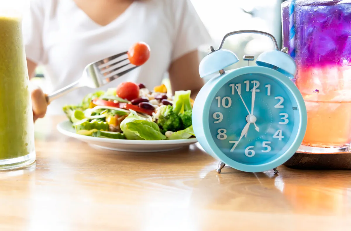 A blue clock used to represent intermittent fasting and a healthy salad. (Nok Lek Travel Lifestyle/Shutterstock)

