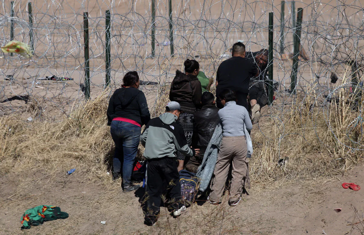 Migrants try to cut a barbed wire fence installed to prevent the entry of illegal immigrants across the Rio Bravo/Grande from Ciudad Juarez, state of Chihuahua, Mexico, on Feb. 12, 2024. (Herika Martinez/AFP/Getty Images)