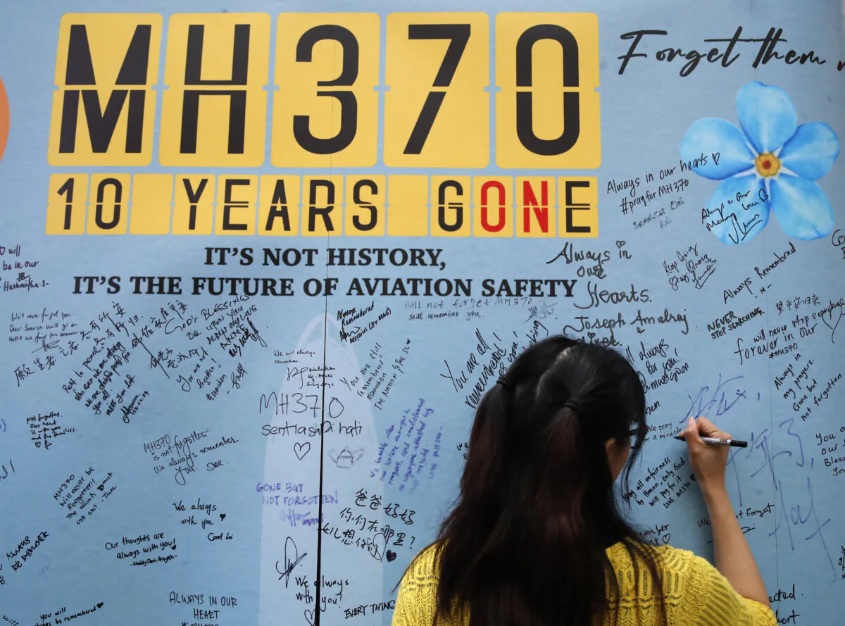 A woman writes well messages on the message board during the 10th annual remembrance event for Malaysia Airlines flight MH370 at a shopping mall in Subang Jaya, on the outskirts of Kuala Lumpur, Malaysia, on March 3, 2024. (FL Wong/AP Photo)
