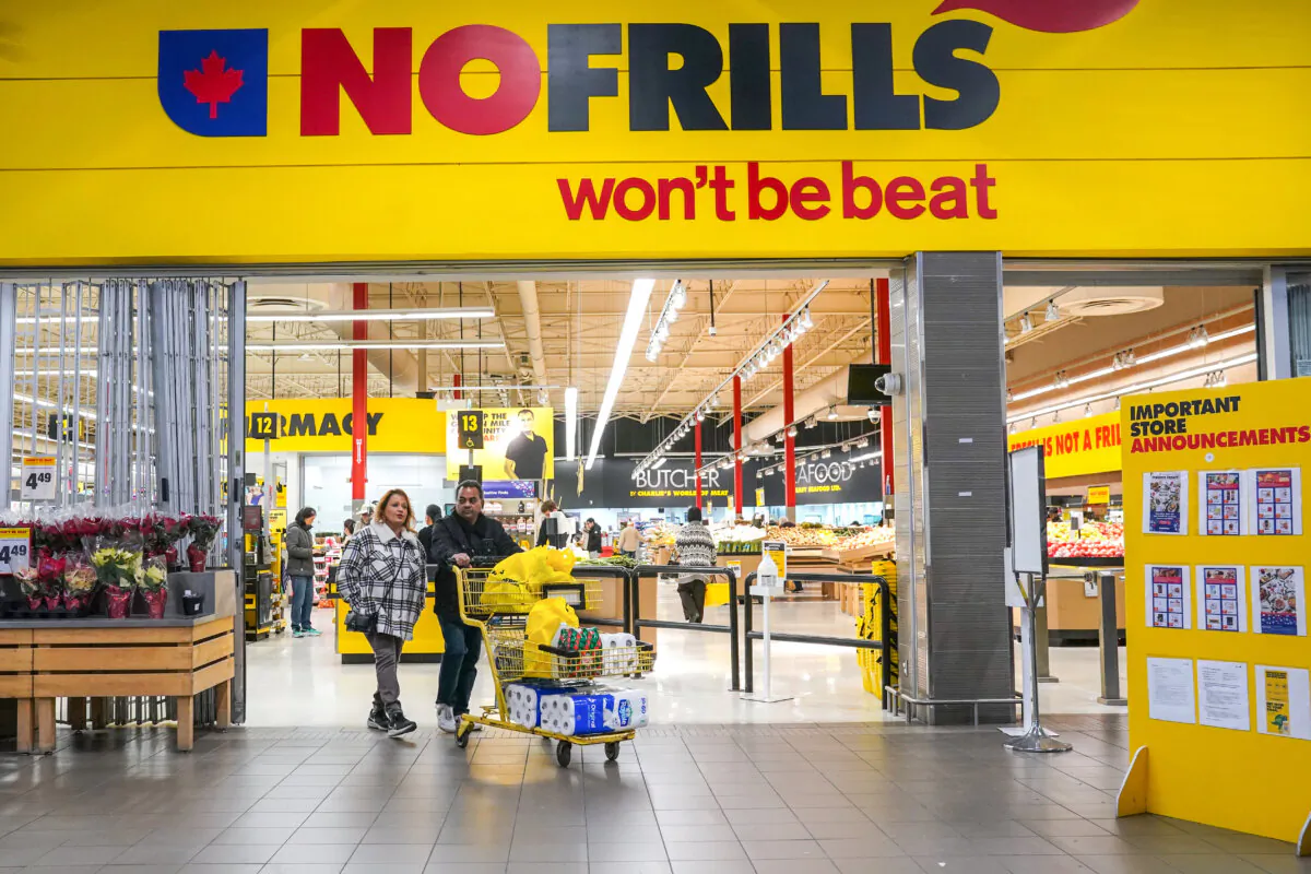 A customer pushes a shopping cart full of groceries from a NoFrills grocery store, in Toronto, on Nov. 23, 2023. (The Canadian Press/Chris Young)