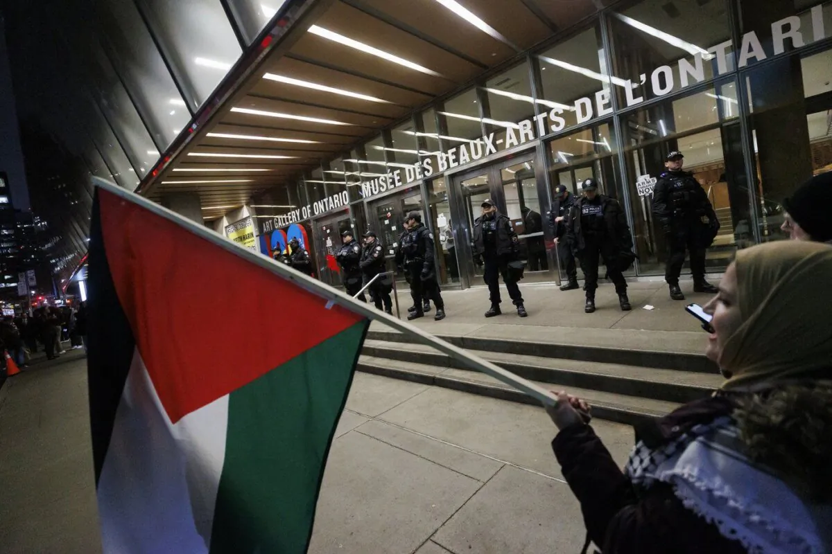Protesters wave flags and sing as police line the entrance to the Art Gallery of Ontario, where a cancelled event for Prime Minister Justin Trudeau and Italy's Prime Minister Giorgia Meloni was to take place, in Toronto on March 2, 2024. (The Canadian Press/Cole Burston)