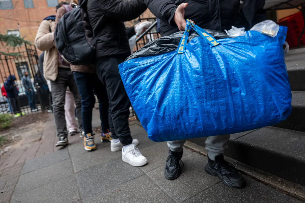 A newly arrived immigrant carries his belongings as he receives an afternoon meal from Trinity Services and Food For the Homeless, across from Tompkins Square Park in New York City on Jan. 24, 2024. (Spencer Platt/Getty Images)