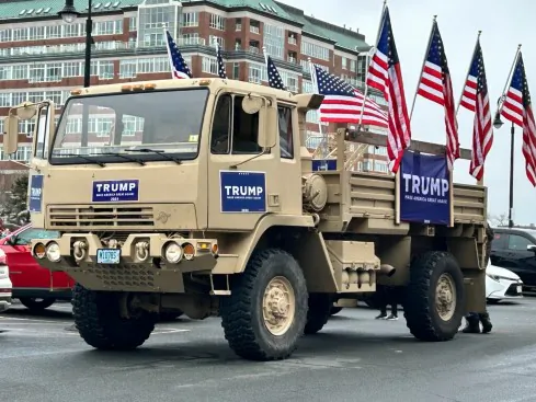A tactical cargo truck draped in signs showing support for former President Donald Trump rolls past the USS Constitution Museum in Boston, on March 3, 2024. (Courtesy of Chester Tam)
