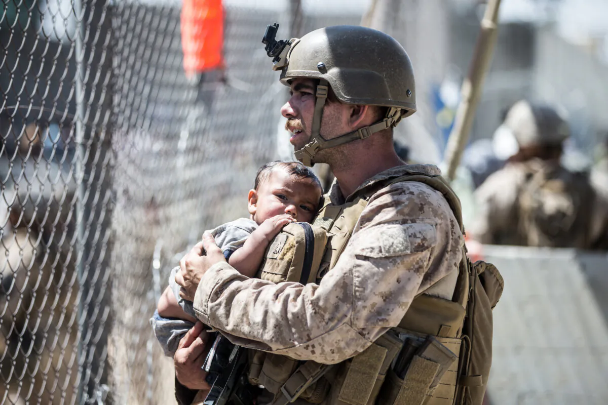 A Marine calms a child during an evacuation at Hamid Karzai International Airport, Kabul, Afghanistan, on Aug. 26, 2021. (Courtesy of Sgt. Samuel Ruiz/U.S. Marine Corps)