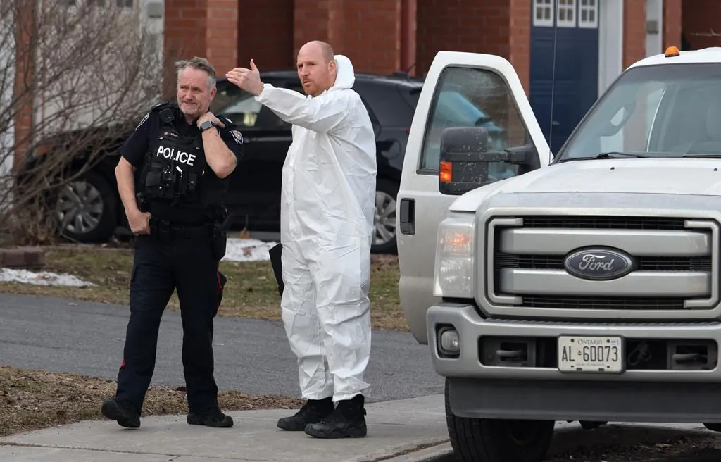 A police officer and a member of the coroner's office talk at the scene of a homicide where six people were found dead in the Barrhaven suburb of Ottawa on March 7, 2024. (The Canadian Press/Patrick Doyle)