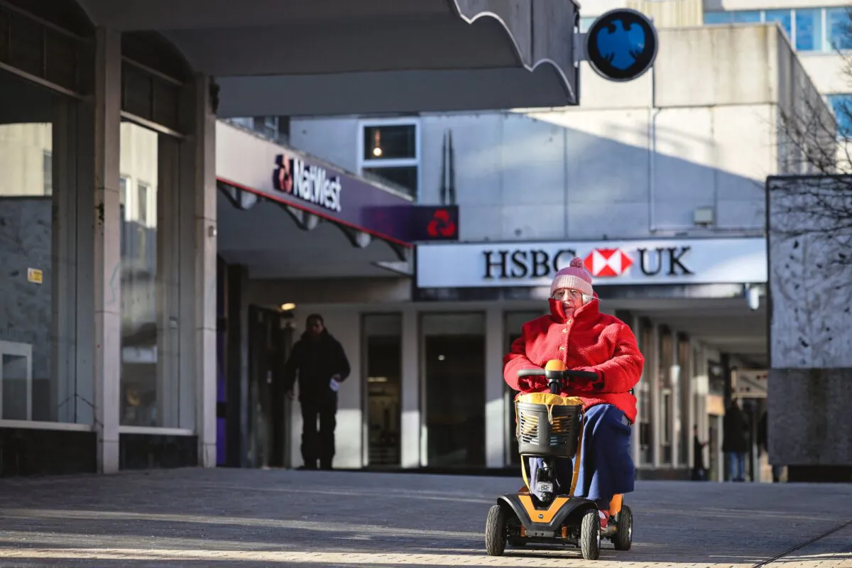 A person rides a mobility scooter past branches of HSBC, NatWest, and Barclays banks on a pedestrianised shopping street in Bracknell town centre on Jan. 10, 2024. (Adrian Dennis/AFP via Getty Images)