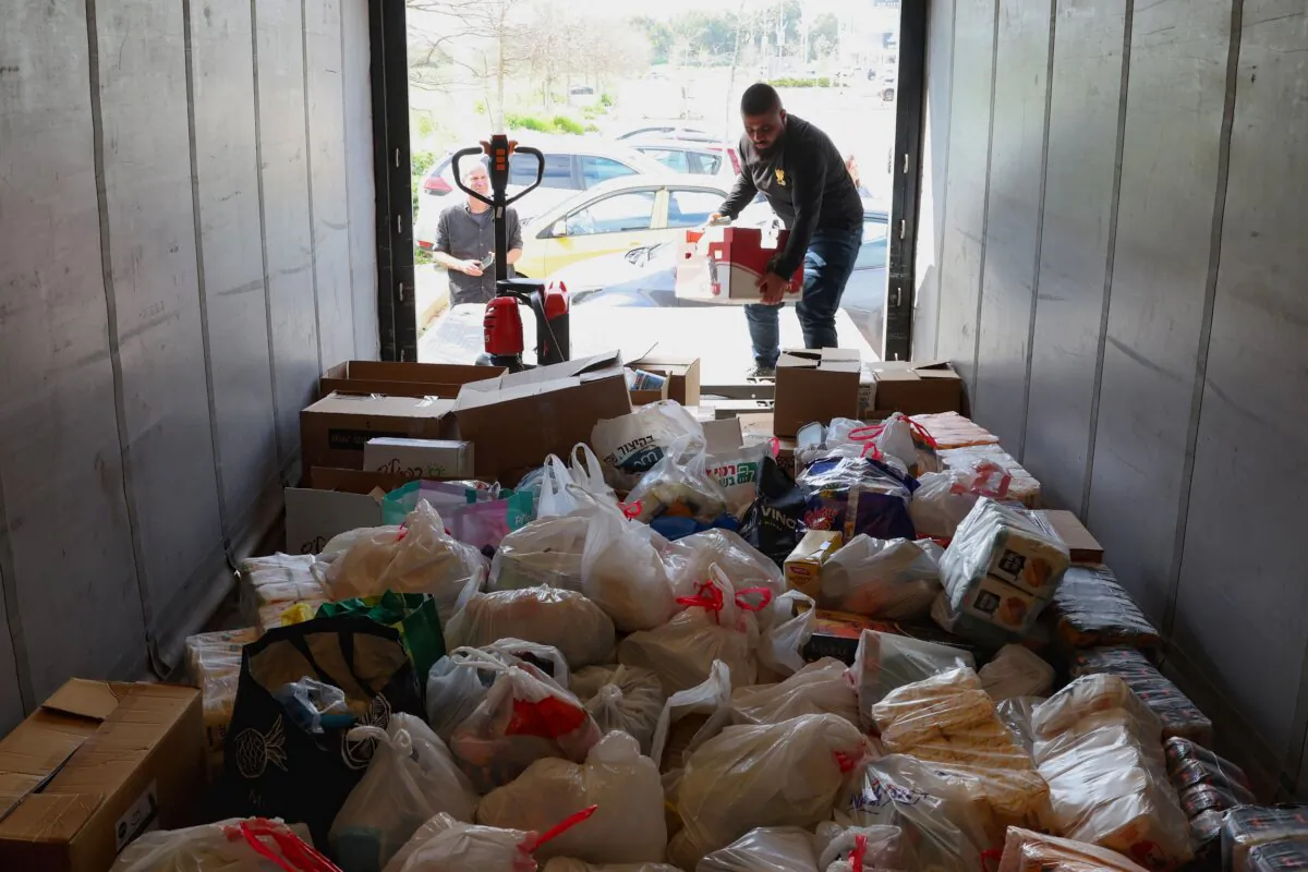 Activists from the "Standing Together" movement fill a truck with food aid at the parking lot of a shopping center of the southern Israeli city of Ashkelon on March 7, 2024, before driving in a convoy toward the border with the Gaza Strip, in a symbolic show of support for Palestinians. (Jack Guez/AFP via Getty Images)