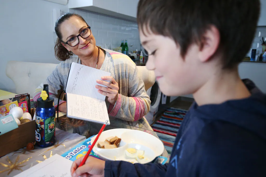 Donna Eddy helps her son Phoenix with school work at their home on April 09, 2020 in Sydney, Australia. (Photo by Brendon Thorne/Getty Images)
