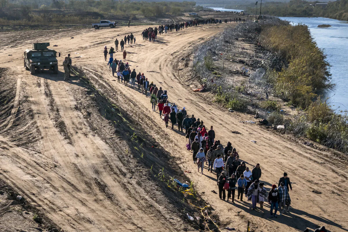 A group of more than 1,000 illegal immigrants walks toward a U.S. Border Patrol field processing center after having crossed the Rio Grande from Mexico, in Eagle Pass, Texas, on Dec. 18, 2023. (John Moore/Getty Images)