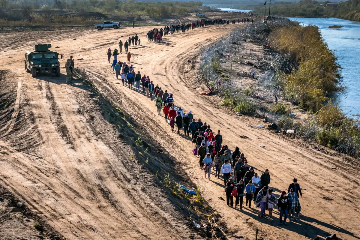 In this aerial view, a group of more than 1,000 illegal immigrants walks toward a U.S. Border Patrol field processing center after crossing the Rio Grande from Mexico, in Eagle Pass, Texas, on Dec. 18, 2023. (John Moore/Getty Images)