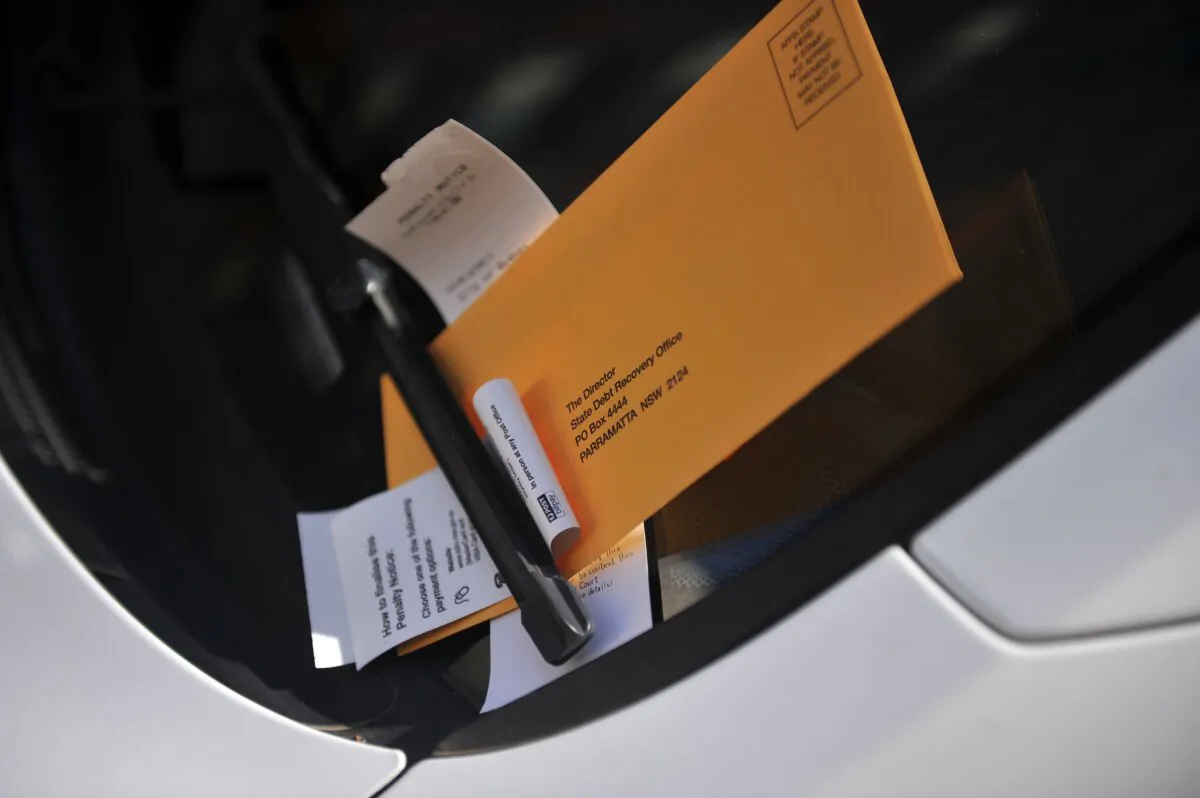 A parking ticket issued by a ranger sits underneath a windscreen wiper on a vehicle in Sydney Australia, on June 17, 2012. (AAP Image/Paul Miller)