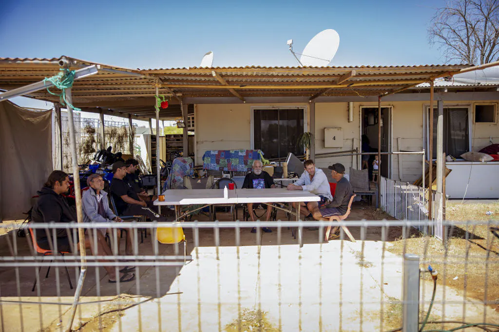 A group of Indigenous people sit at the front of one of the houses in a community in Pia Wadjarri, Australia, on Oct. 4, 2023. (Tamati Smith/Getty Images)
