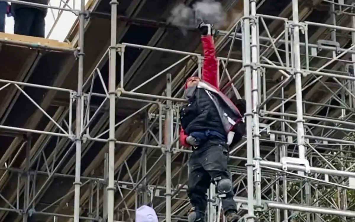 A man identified by the FBI as John Banuelos fires two shots into the air from scaffolding near the U.S. Capitol on Jan. 6, 2021. (Derrick Evans/Screenshot via The Epoch Times)