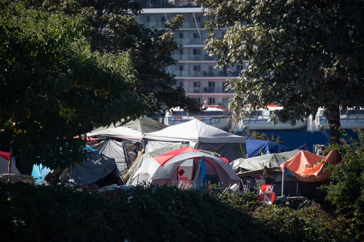 A person sits in a tent at a homeless encampment at Crab Park in Vancouver, on Aug. 14, 2022. (The Canadian Press/Darryl Dyck)