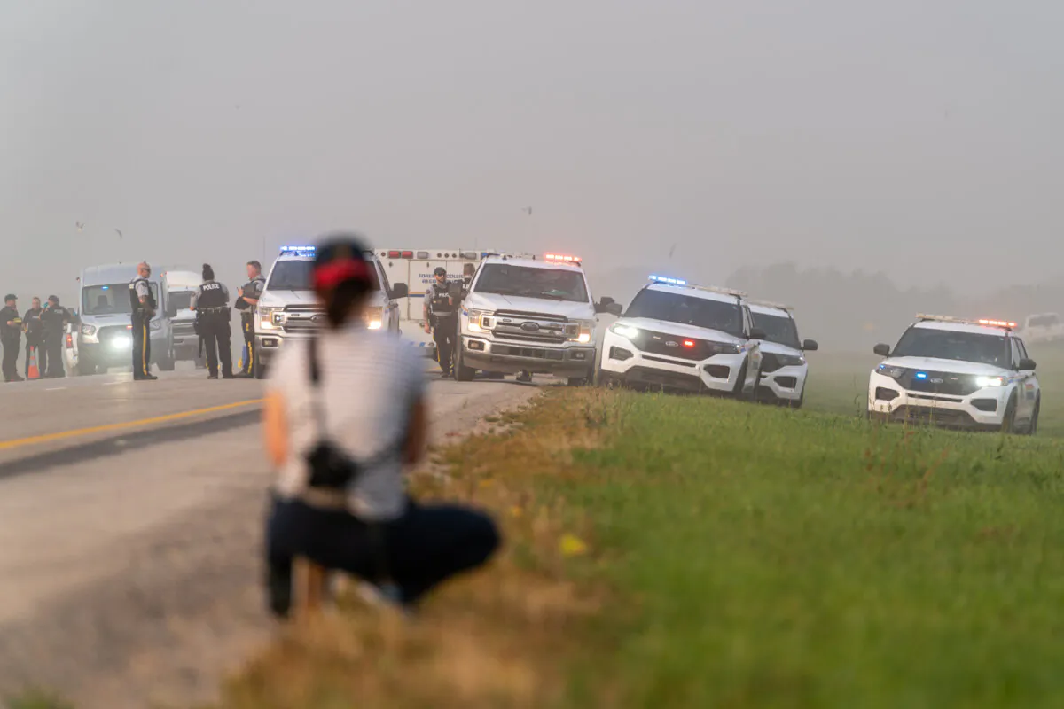 Police and investigators are seen at the side of the road outside Rosthern, Sask., on Sept. 7, 2022. (The Canadian Press/Heywood Yu)