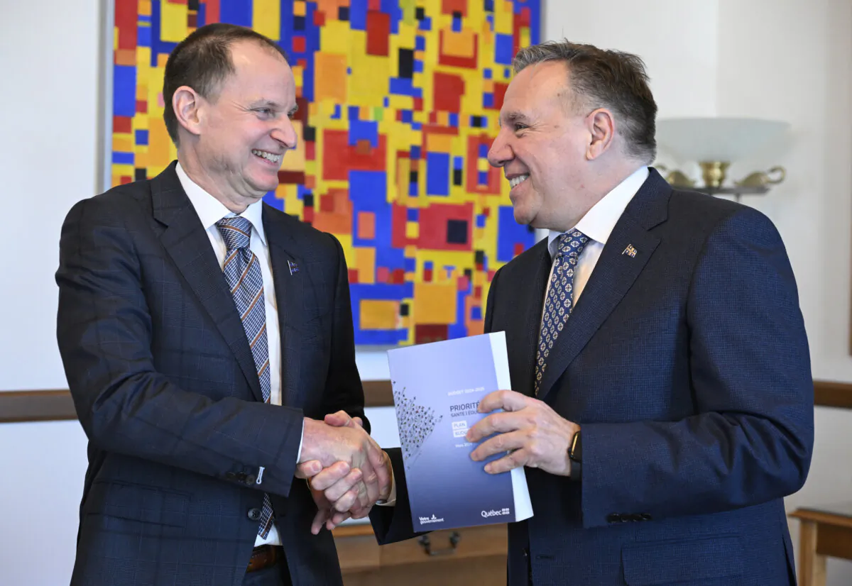 Quebec Finance Minister Eric Girard shakes hand with Quebec Premier Francois Legault after giving him a copy of his provincial budget, at the premier’s office in Quebec City on Mar. 12, 2024. (The Canadian Press/Jacques Boissinot)