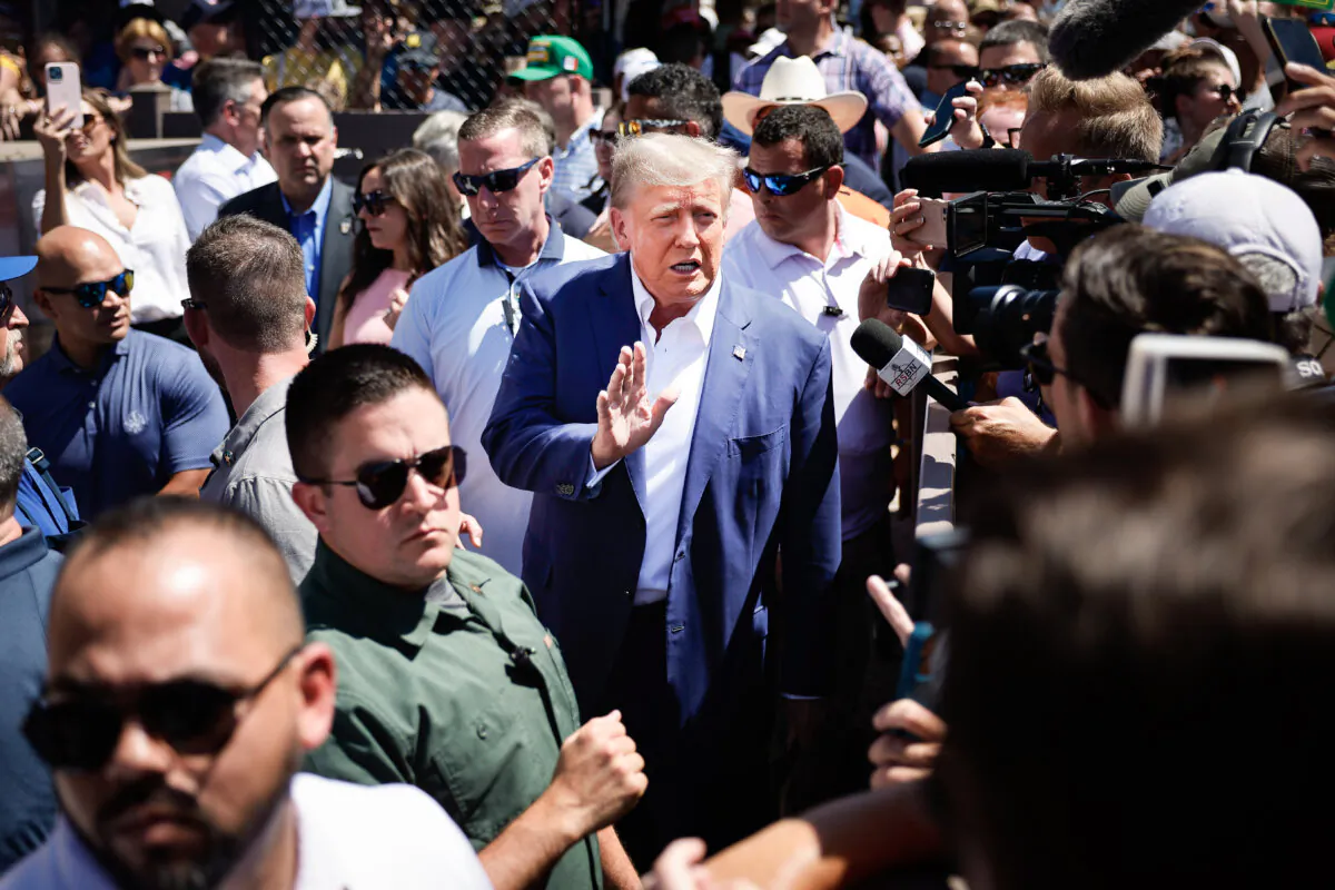 Surrounded by campaign staff and members of the U.S. Secret Service, former U.S. President Donald Trump (C) waves to supporters as he visits the Iowa Pork Producers Tent at the Iowa State Fair in Des Moines, Iowa, on Aug. 12, 2023. (Chip Somodevilla/Getty Images)